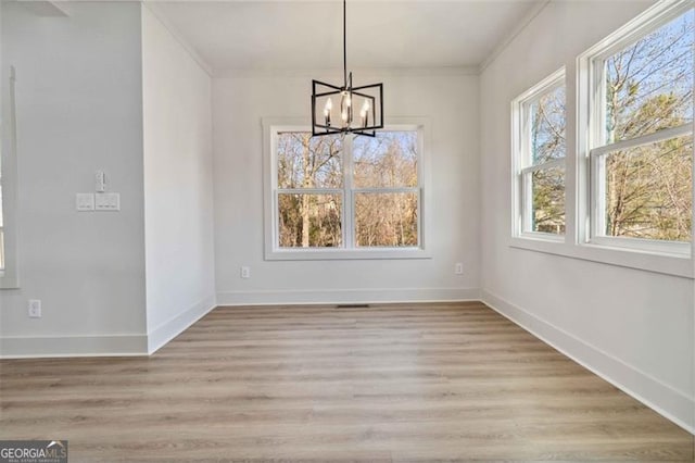 unfurnished dining area featuring light wood-type flooring, an inviting chandelier, and ornamental molding