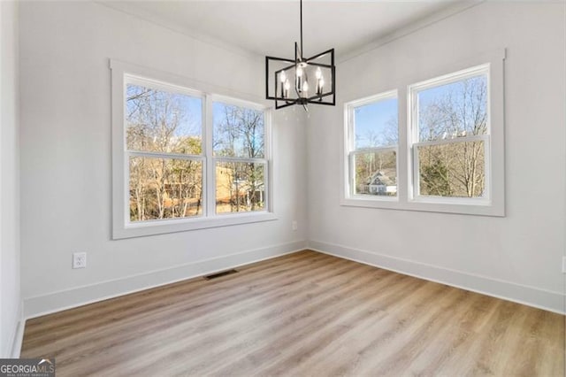 unfurnished dining area with a notable chandelier, crown molding, and light hardwood / wood-style flooring