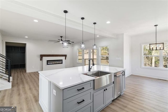 kitchen featuring hanging light fixtures, dishwasher, a kitchen island with sink, and gray cabinetry