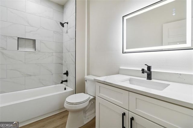 full bathroom featuring toilet, tiled shower / bath, hardwood / wood-style flooring, and vanity