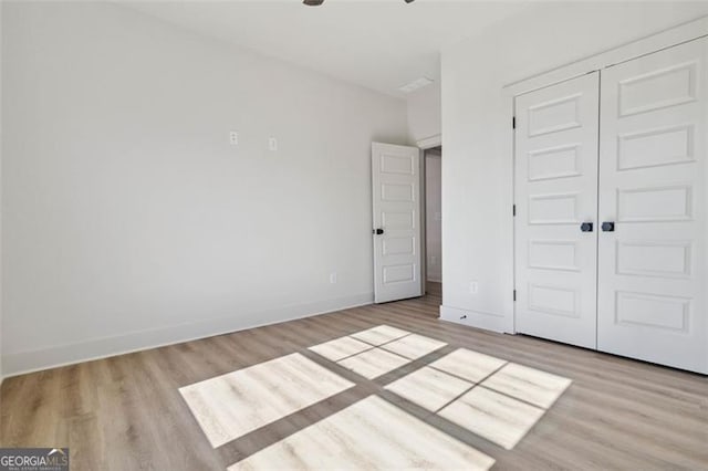 unfurnished bedroom with a closet and light hardwood / wood-style flooring