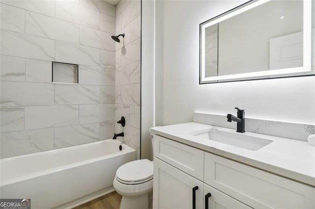 full bathroom featuring hardwood / wood-style flooring, tiled shower / bath combo, vanity, and toilet