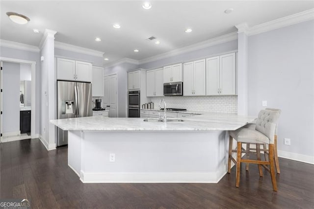 kitchen with tasteful backsplash, appliances with stainless steel finishes, a peninsula, white cabinetry, and a sink