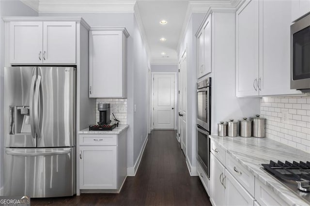 kitchen with light stone countertops, white cabinetry, stainless steel appliances, and ornamental molding