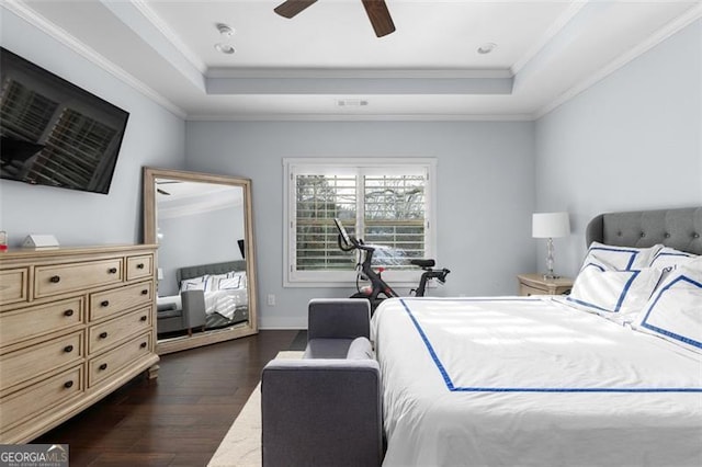 bedroom featuring baseboards, a raised ceiling, dark wood finished floors, and crown molding