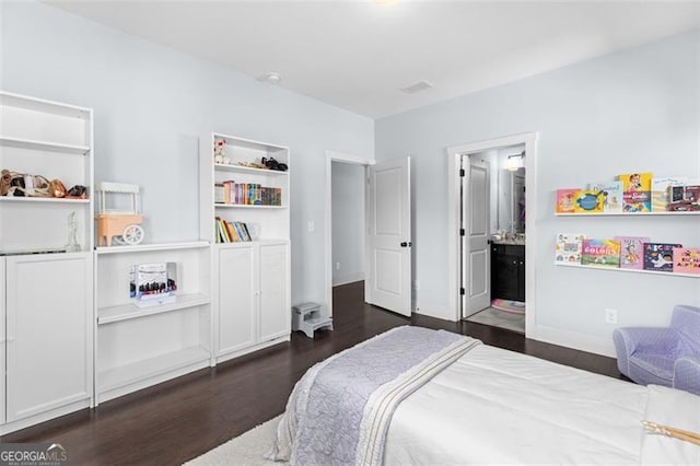 bedroom featuring ensuite bathroom and dark wood finished floors