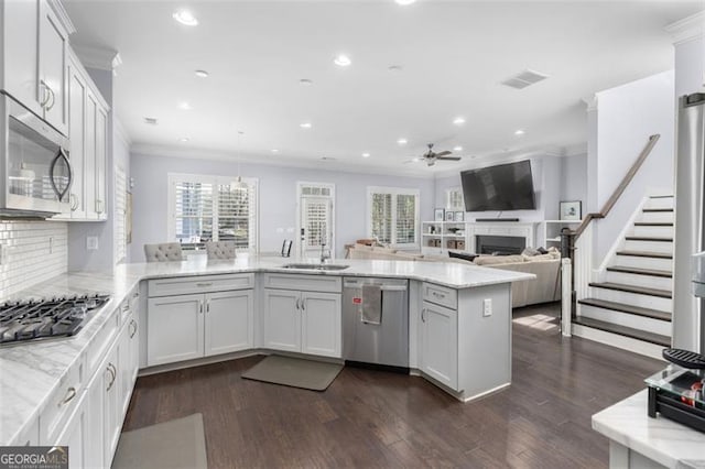 kitchen featuring stainless steel appliances, visible vents, ornamental molding, light stone countertops, and a peninsula