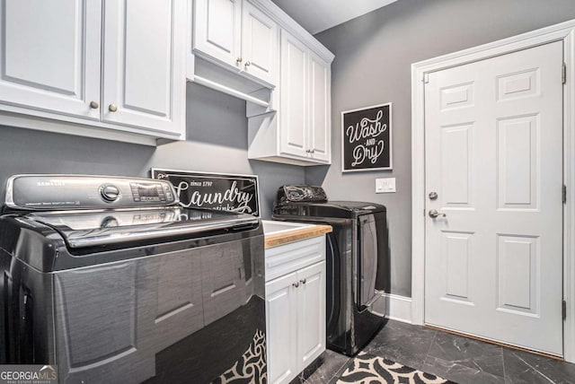 clothes washing area featuring washing machine and dryer and cabinets