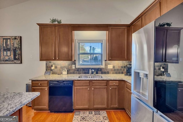 kitchen featuring light stone countertops, light hardwood / wood-style floors, dishwasher, and sink