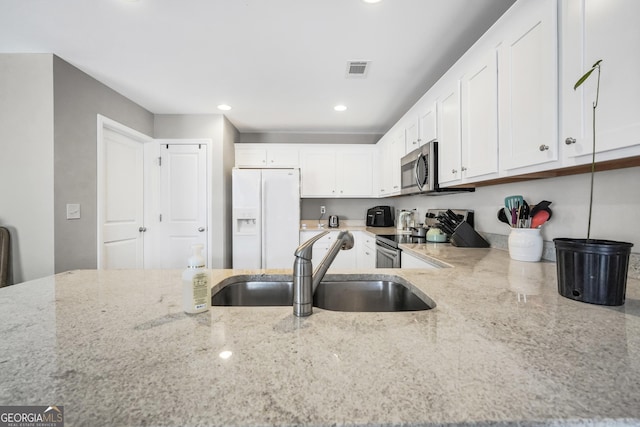 kitchen with light stone countertops, sink, white cabinetry, and stainless steel appliances