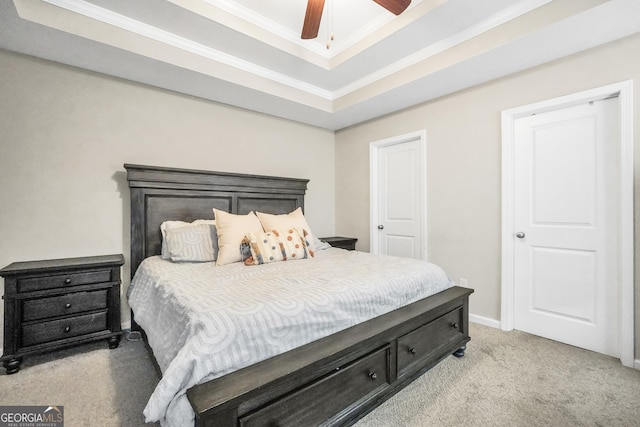 carpeted bedroom featuring ceiling fan, crown molding, and a tray ceiling