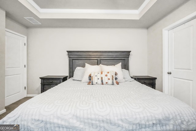 carpeted bedroom featuring a tray ceiling and ornamental molding