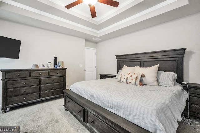 carpeted bedroom with ceiling fan, ornamental molding, and a raised ceiling