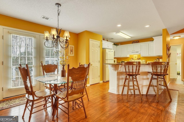 dining room featuring light hardwood / wood-style floors, a textured ceiling, and a chandelier