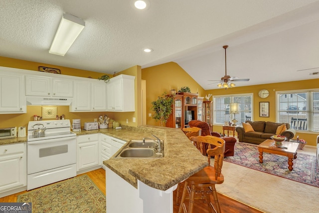 kitchen featuring a kitchen bar, white cabinetry, sink, kitchen peninsula, and electric range