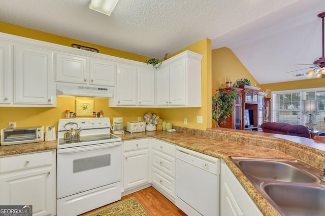 kitchen featuring white appliances, a textured ceiling, white cabinetry, sink, and vaulted ceiling