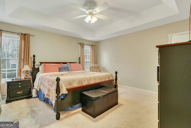 carpeted bedroom featuring ceiling fan and a tray ceiling