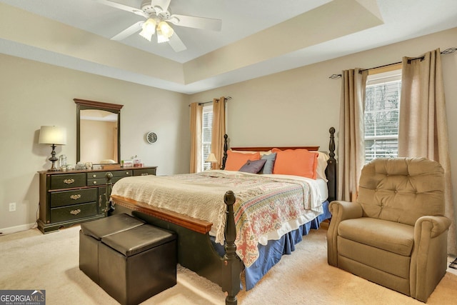 carpeted bedroom featuring ceiling fan and a raised ceiling