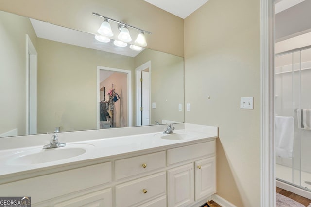 bathroom featuring a shower with shower door and vanity