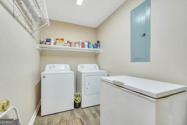 clothes washing area with light hardwood / wood-style floors, electric panel, and washing machine and dryer