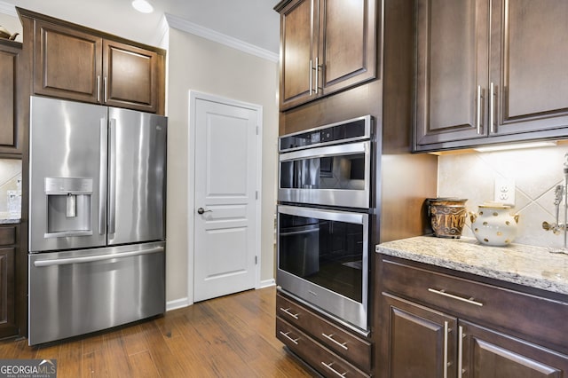 kitchen featuring stainless steel appliances, ornamental molding, dark brown cabinets, and tasteful backsplash