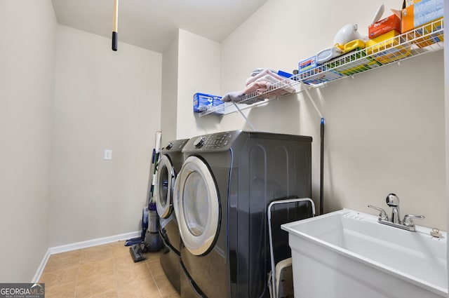 laundry room with laundry area, light tile patterned floors, baseboards, washing machine and dryer, and a sink