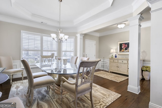 dining room featuring dark wood-style floors, a raised ceiling, decorative columns, and an inviting chandelier