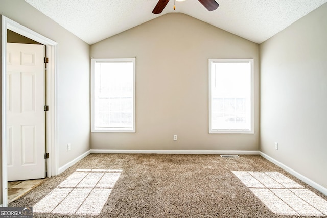 carpeted empty room with vaulted ceiling, ceiling fan, a healthy amount of sunlight, and a textured ceiling