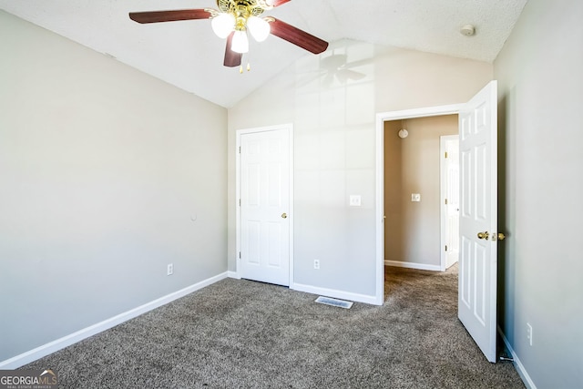 unfurnished bedroom with ceiling fan, dark carpet, and vaulted ceiling