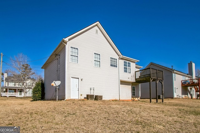 back of house with a wooden deck and a lawn