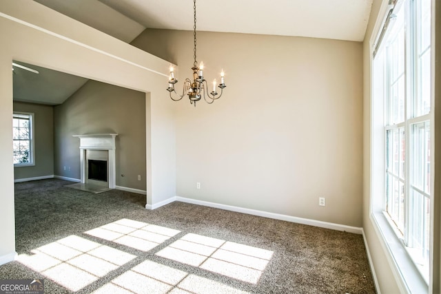 carpeted spare room with an inviting chandelier and lofted ceiling