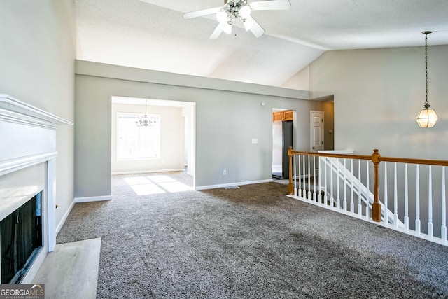 unfurnished living room with ceiling fan with notable chandelier, carpet, and vaulted ceiling