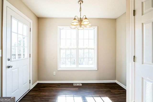 interior space with a textured ceiling, an inviting chandelier, and dark hardwood / wood-style floors