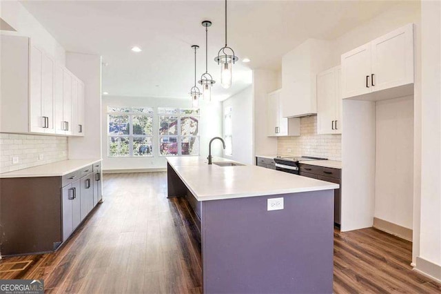 kitchen with pendant lighting, a center island with sink, stainless steel electric range, sink, and white cabinets