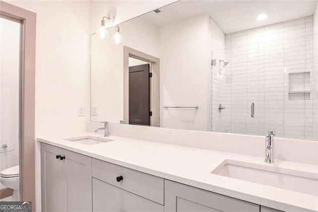 bathroom featuring toilet, vanity, and a shower with shower door