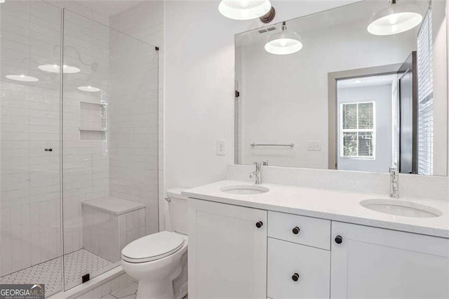 bathroom featuring toilet, a shower with door, and vanity