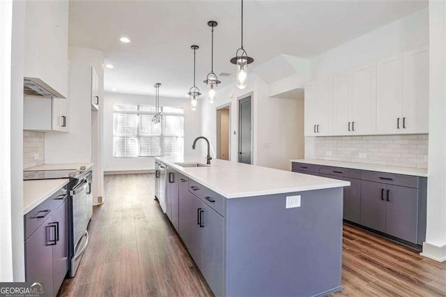 kitchen with a center island with sink, stainless steel electric range, sink, white cabinetry, and hanging light fixtures