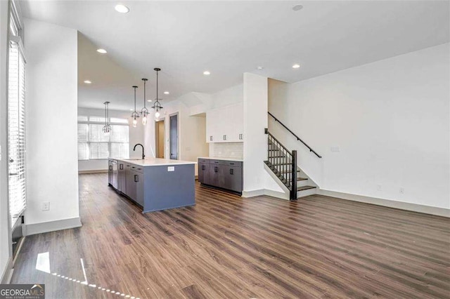 kitchen with decorative light fixtures, sink, a healthy amount of sunlight, an island with sink, and white cabinets