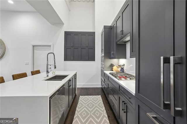 kitchen featuring stainless steel appliances, an island with sink, sink, dark hardwood / wood-style floors, and a breakfast bar area