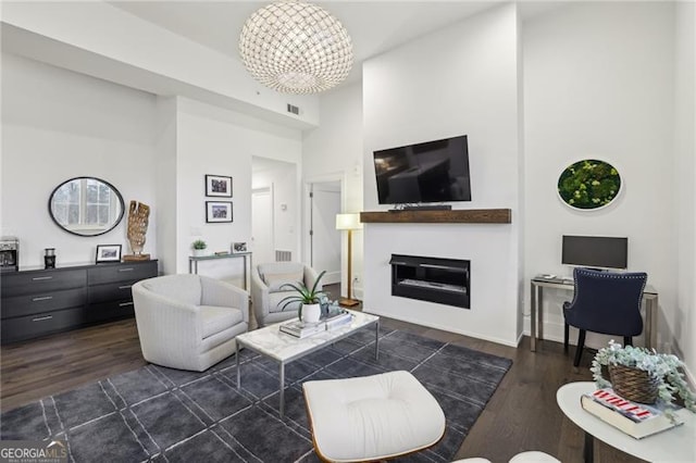 living room featuring dark hardwood / wood-style flooring, a towering ceiling, and an inviting chandelier