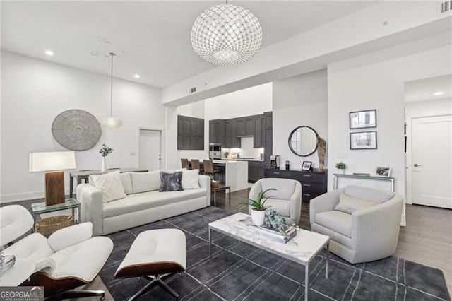 living room featuring a high ceiling, dark hardwood / wood-style flooring, and an inviting chandelier