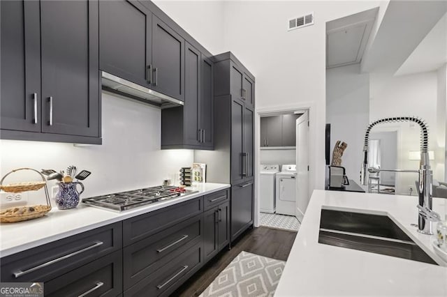 kitchen featuring separate washer and dryer, dark hardwood / wood-style floors, stainless steel gas stovetop, and sink