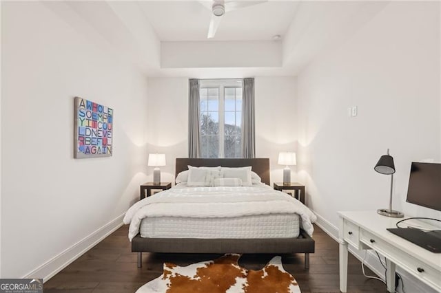 bedroom with ceiling fan, dark hardwood / wood-style floors, and a raised ceiling