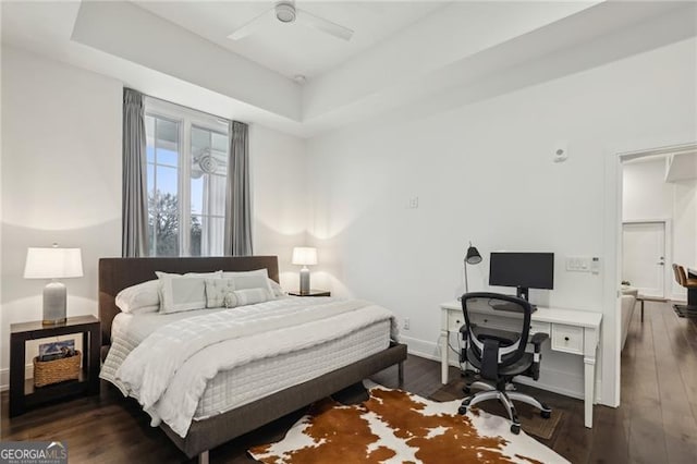 bedroom with ceiling fan, dark hardwood / wood-style flooring, and a tray ceiling