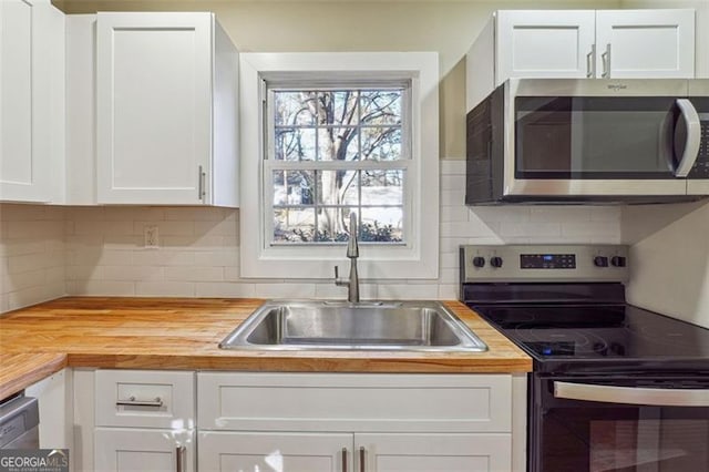 kitchen with white cabinets, butcher block counters, and stainless steel appliances