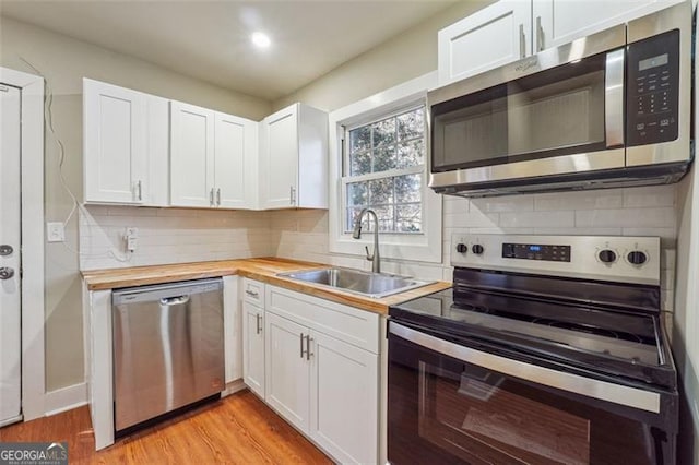 kitchen with wood counters, white cabinetry, appliances with stainless steel finishes, tasteful backsplash, and sink