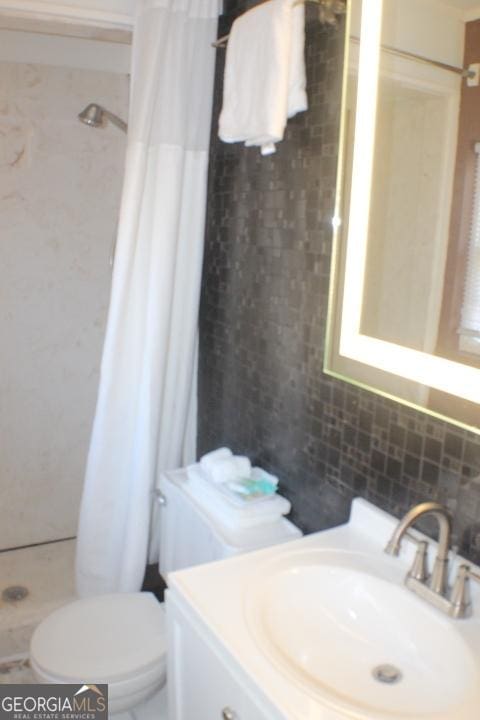 bathroom with toilet, vanity, tasteful backsplash, and a shower with shower curtain