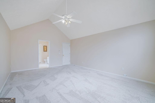 unfurnished bedroom featuring ceiling fan, ensuite bathroom, light colored carpet, and high vaulted ceiling