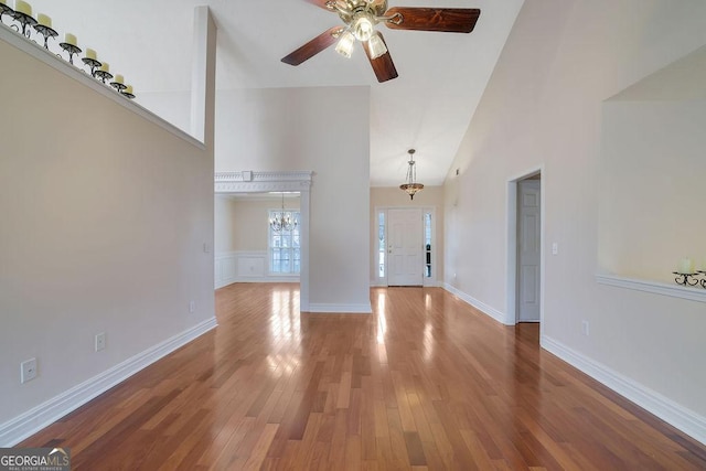 unfurnished living room with hardwood / wood-style flooring, high vaulted ceiling, and ceiling fan