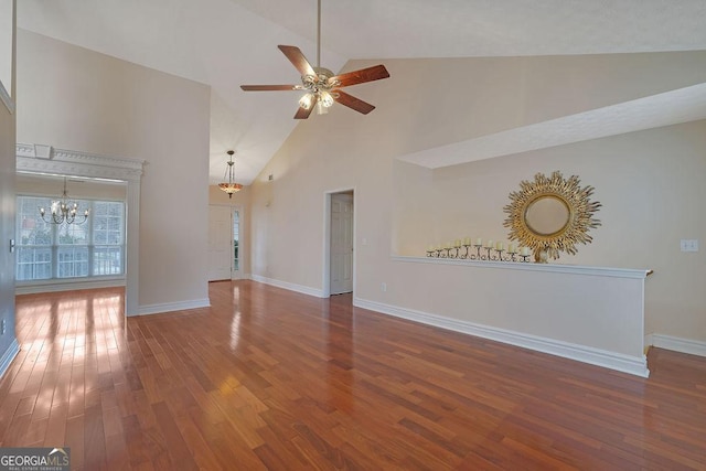 unfurnished living room featuring ceiling fan with notable chandelier, high vaulted ceiling, and wood-type flooring